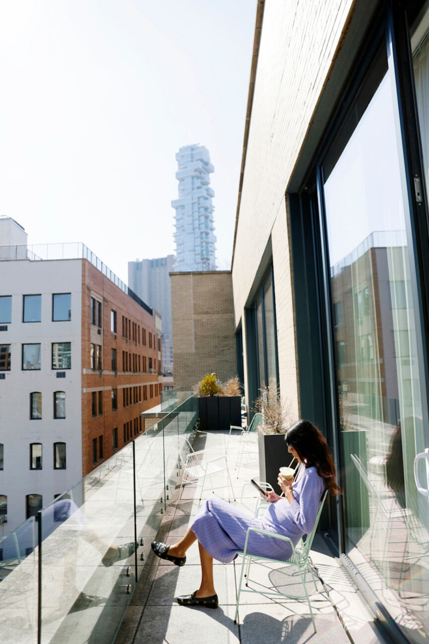 Woman drinking smoothie on balcony.