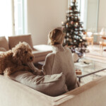 Woman putting dog in front of Christmas tree