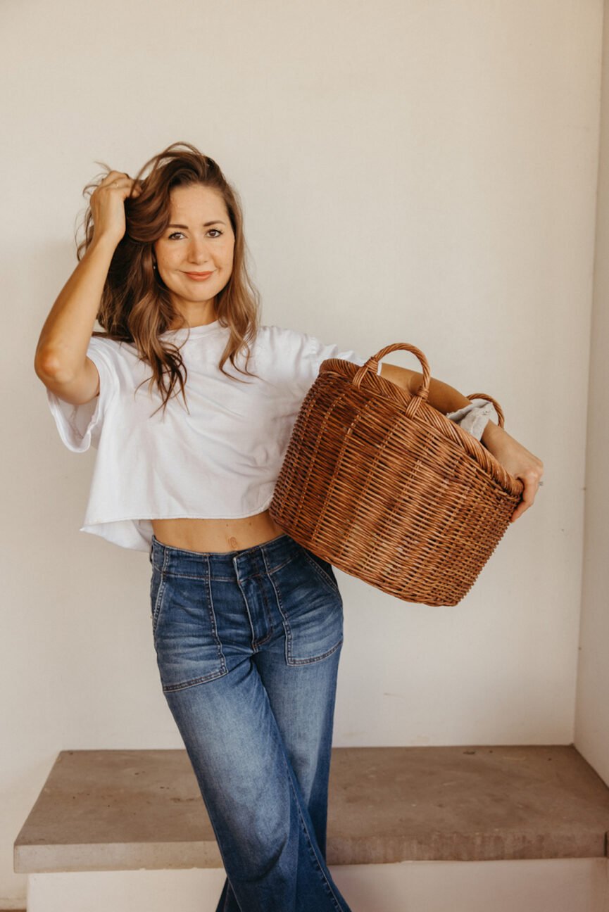 Camille Styles carrying laundry basket while doing healthy weekend habits.