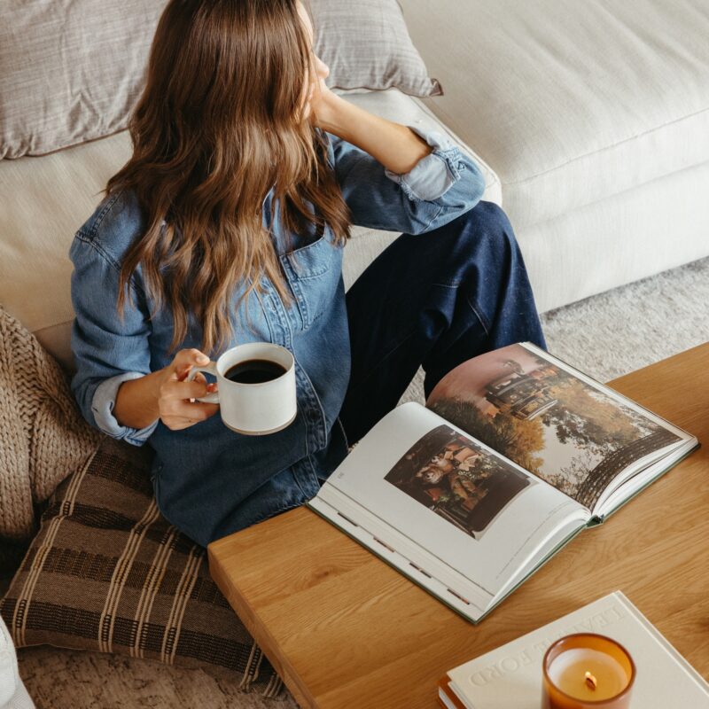camille sitting at coffee table with book and coffee