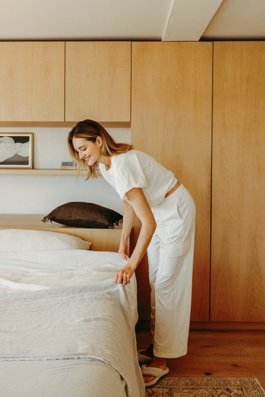 Woman making bed as a part of her morning rituals for clarity.
