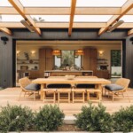 Open pocket doors connect Casa Zuma’s kitchen and great room to an outdoor dining terrace surrounded by greenery.